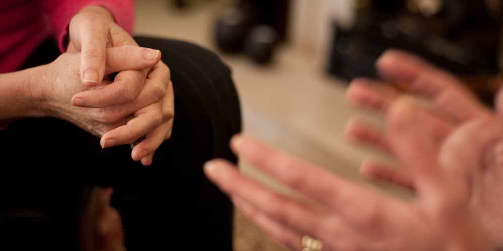 Mãos de duas pessoas frente a frente durante uma conversa de aconselhamento