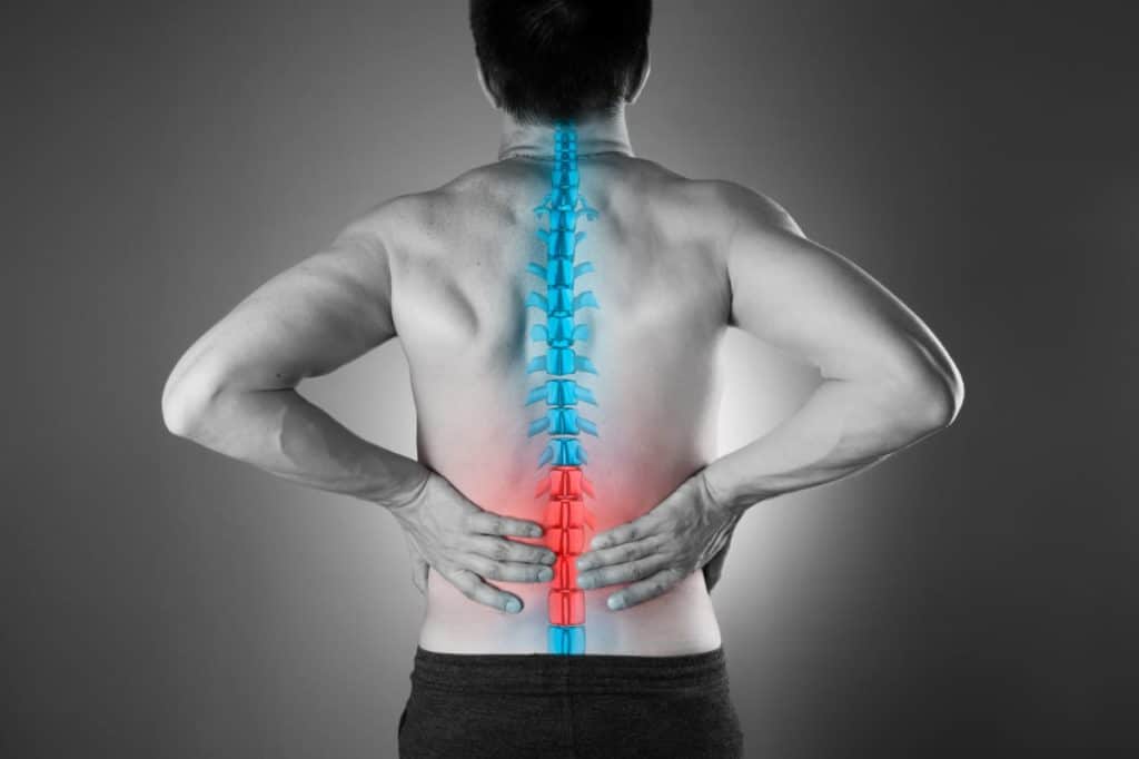Vista posterior do tronco de um homem com a coluna vertebral sobreposta em azul e a região lombar baixa destacada em vermelho, indicando dor.