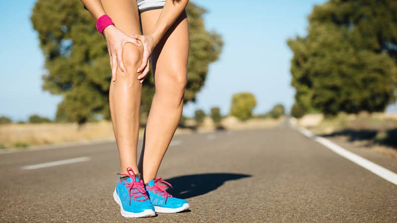 Modelo muscular de um corredor em movimento destacando o trato iliotibial na lateral da coxa e o local da dor próximo ao quadril