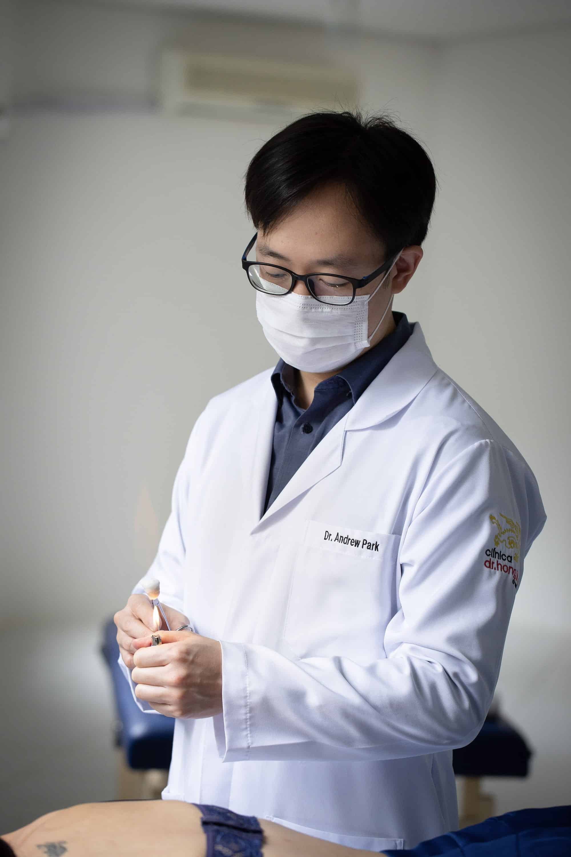 Dr. Andrew Park acende o algodão preso a uma pinça metálica.