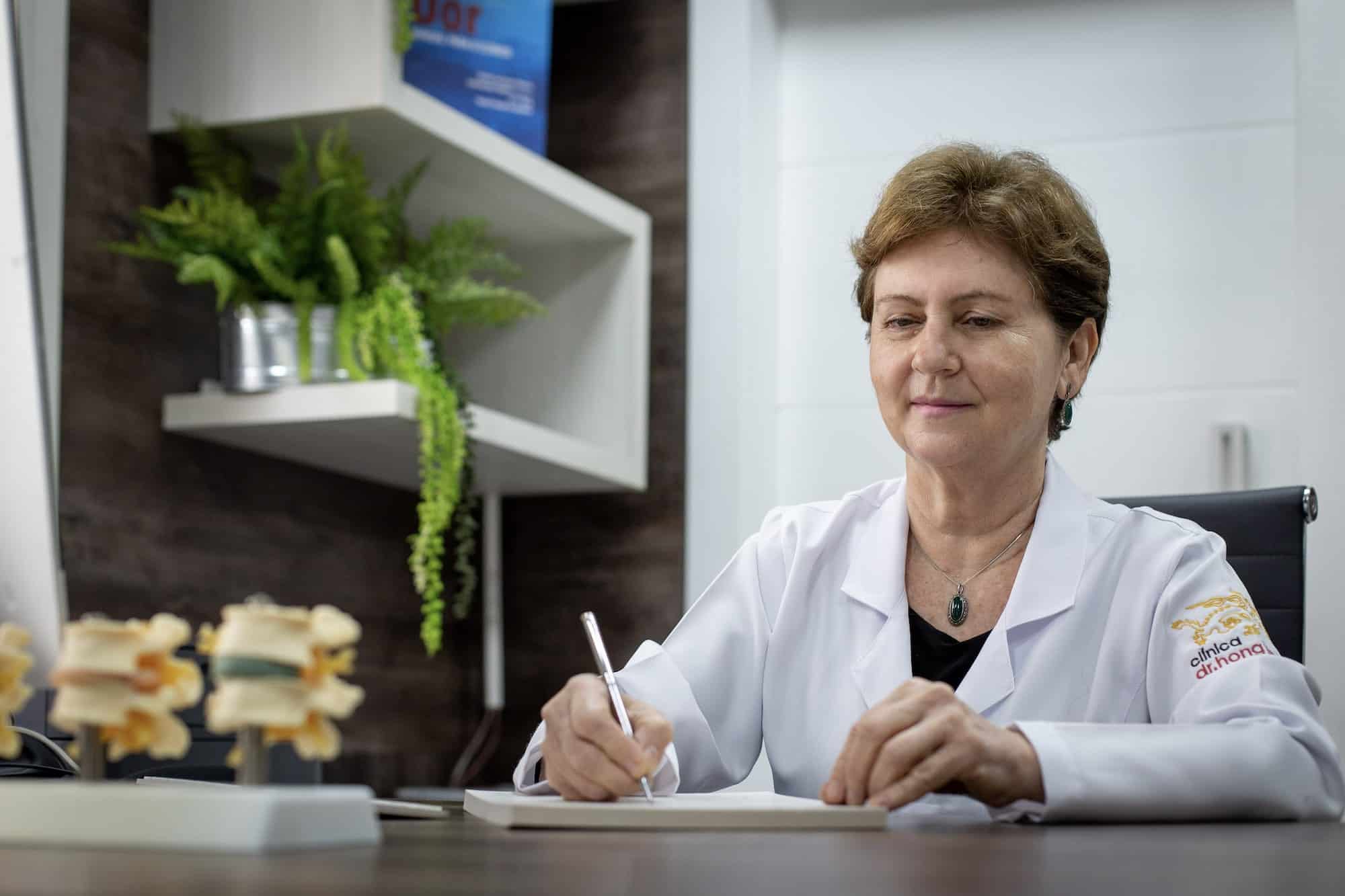 Dra. Célia Yunes Portiolli escreve à mesa do consultório.