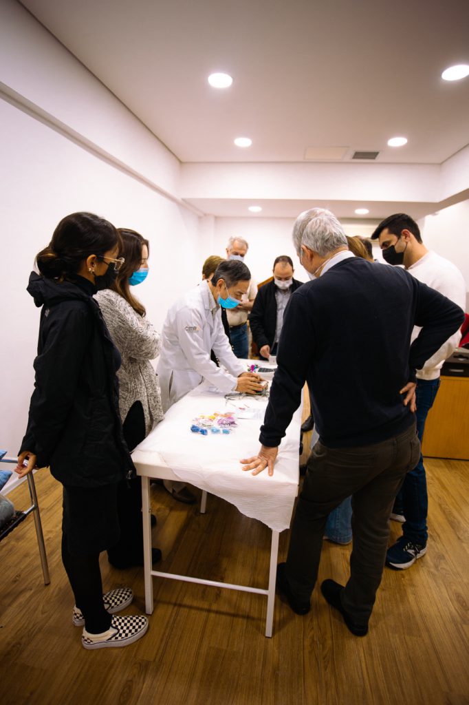 Dr. Hong Jin Pai ensinando acupuntura a alunos ao redor de uma maca na clínica