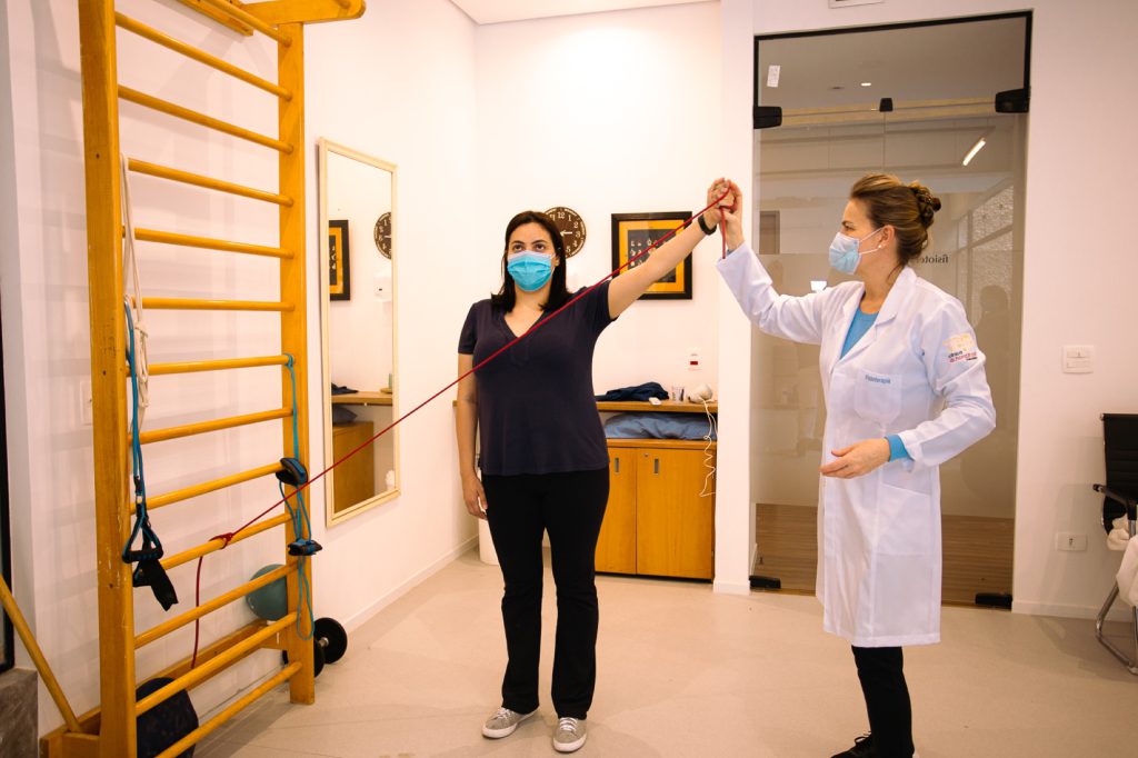 Exercício de ombro com faixa elástica orientado por fisioterapeuta