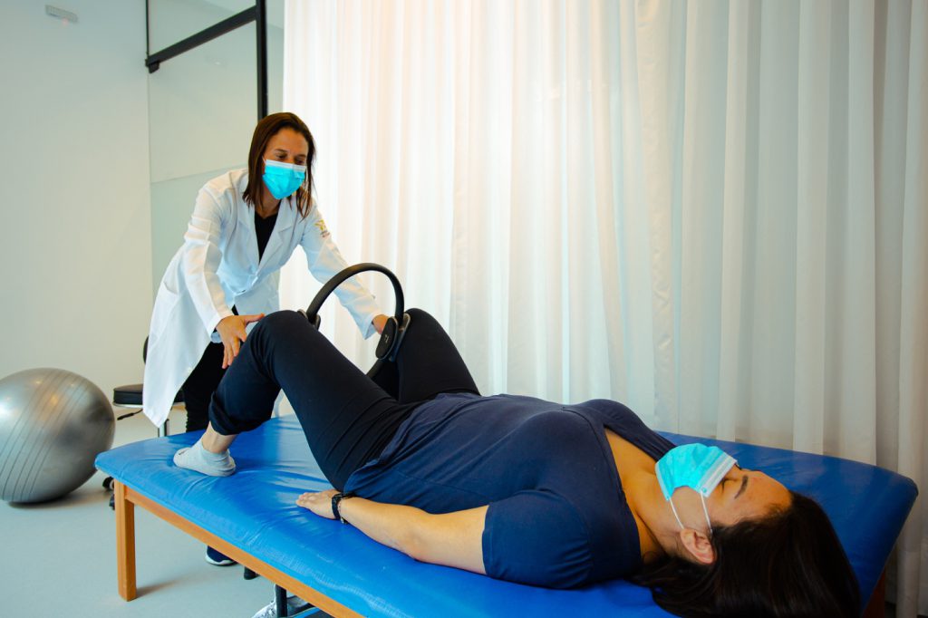 Fisioterapeuta orientando exercício com aro de Pilates em sessão individual