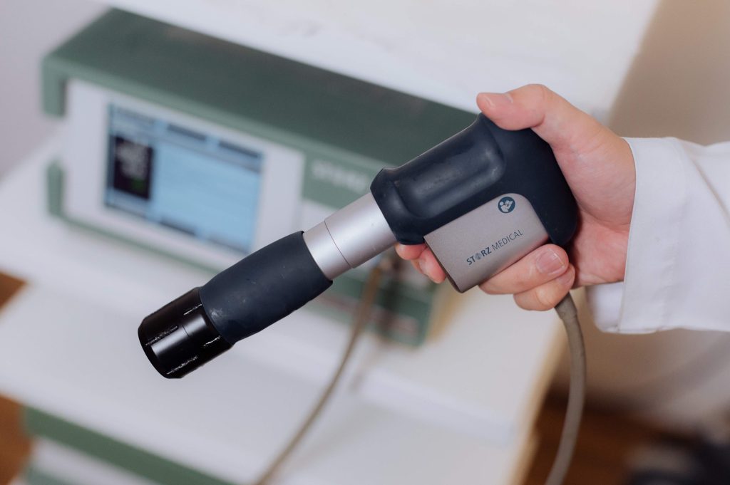Tendinite de Aquiles: causas e tratamento 2 Aplicador radial de ondas de choque Storz Medical em uso, com o console do aparelho ao fundo, na clínica