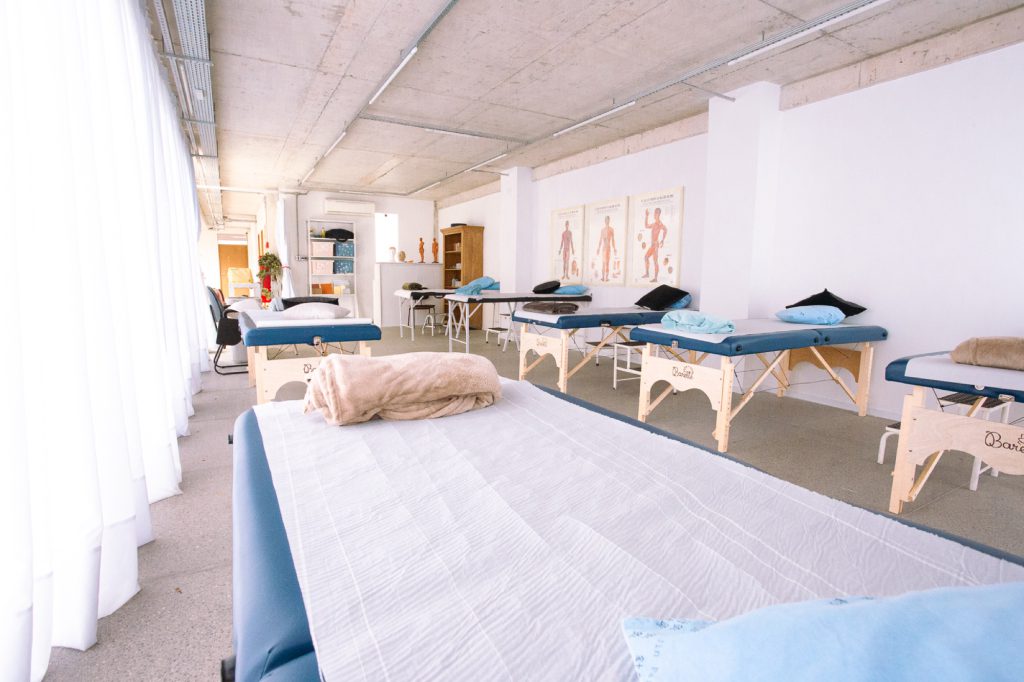 Dor na costela: neurite intercostal, fratura e mais 11 Vista em ângulo baixo da sala de fisioterapia com fileiras de macas de madeira na clínica