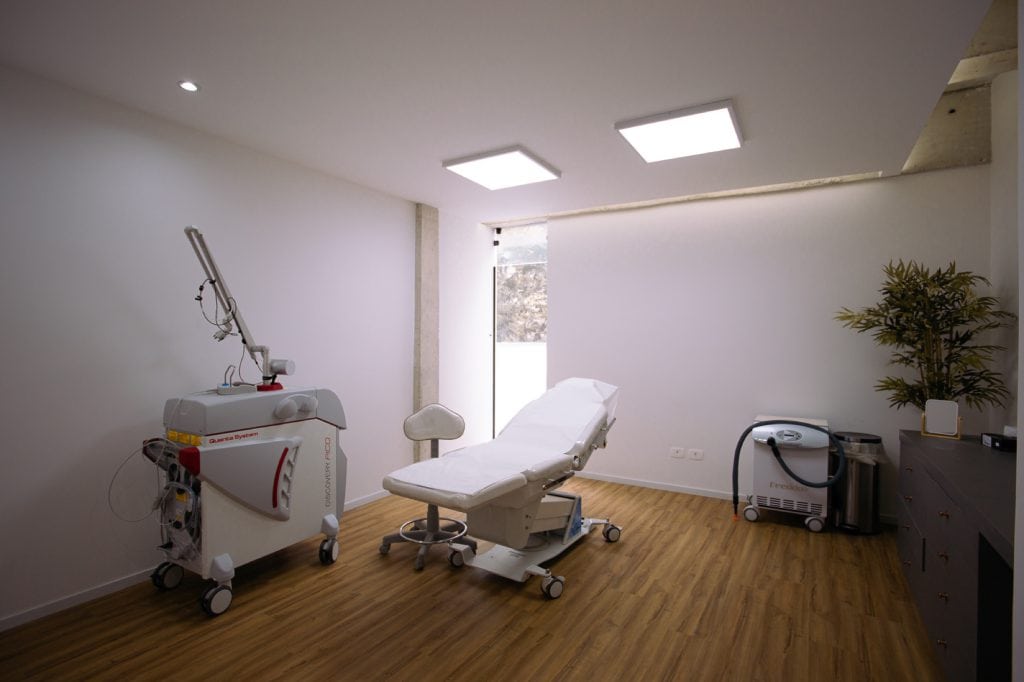 Sala com equipamento de laser Pico, cadeira de procedimento e maca branca